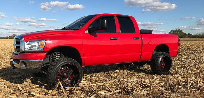 Lifted red Ram in farm field